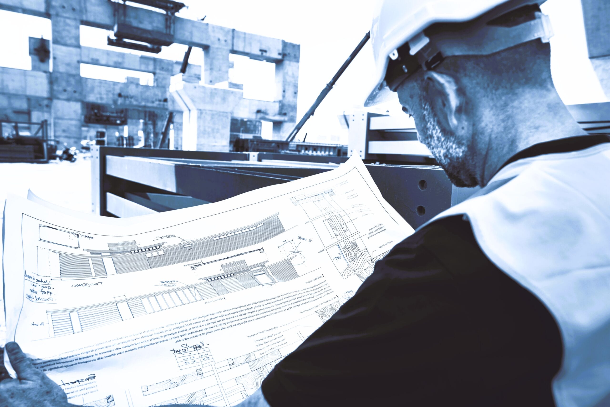 Worker reviewing blueprints for residential and commercial construction.
